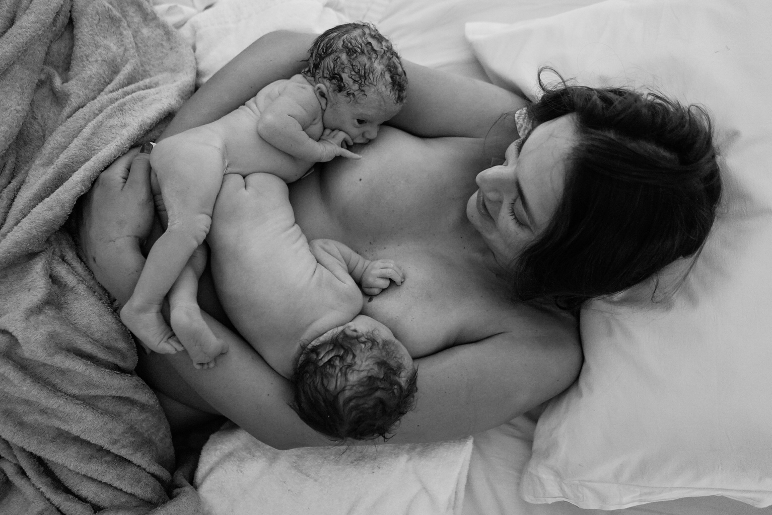 imagem preto e branco de mãe amamentando dois bebês ao mesmo tempo na amamentação em tandem