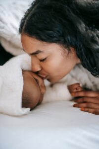 Mãe encostando o rosto no bebê recém-nascido enrolado em manta