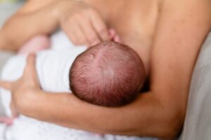 Mãe amamentando recém-nascido no colo, vista de cima