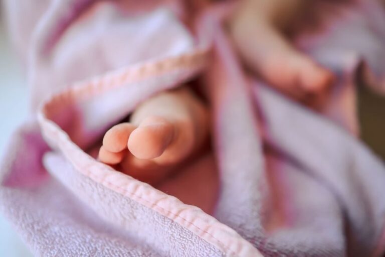 Pezinhos de recém-nascido envoltos em manta rosa