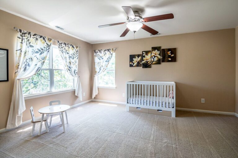 Quarto de bebê amplo e organizado, com berço, mesinha branca e cadeira
